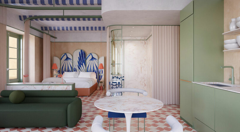 Modern studio apartment with pastel green kitchen, round marble dining table, dark green sofa, and double bed; geometric tiles and blue-striped ceiling accents throughout.