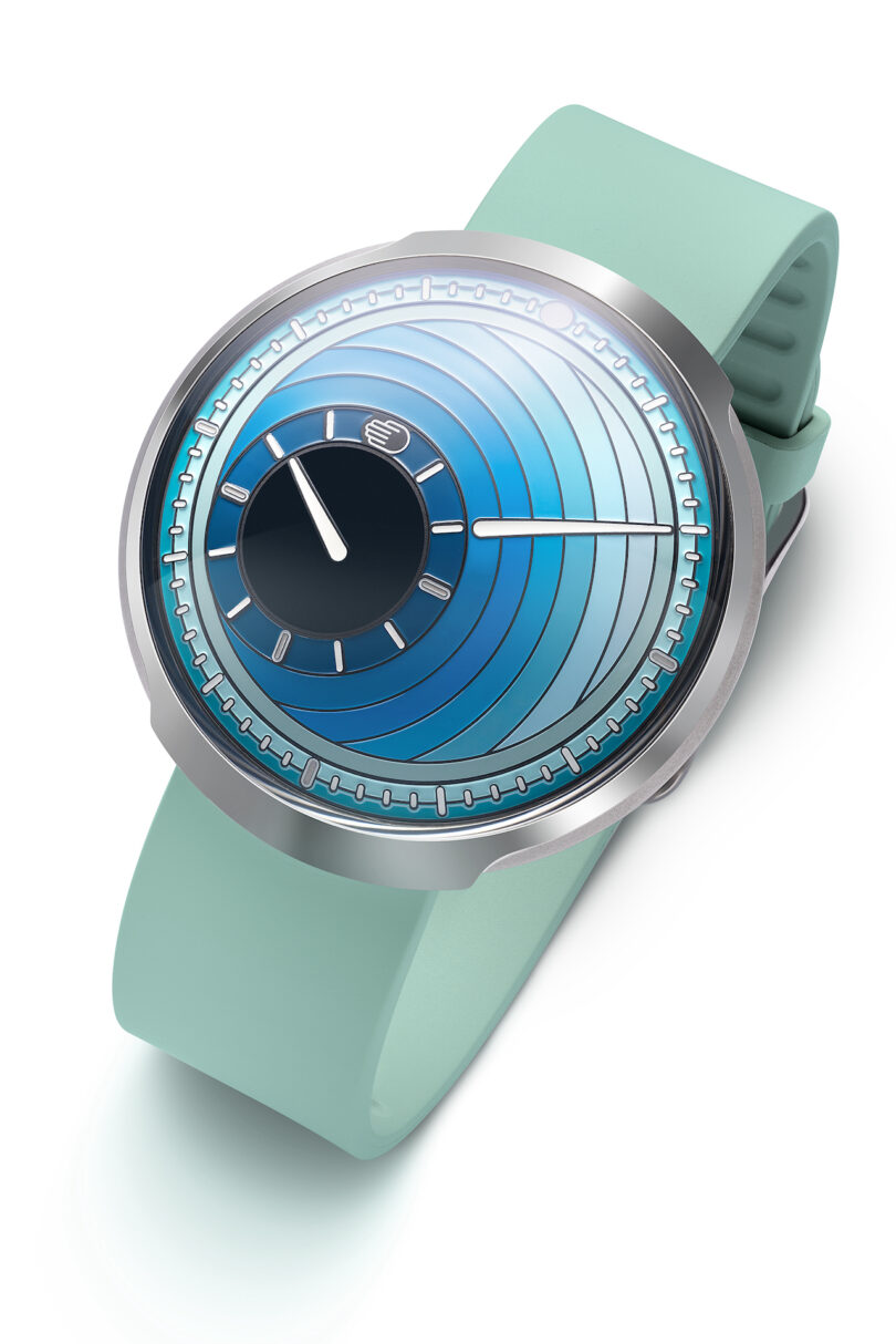 A modern wristwatch with a turquoise strap and a circular blue gradient dial displaying minimalist white hands and markers