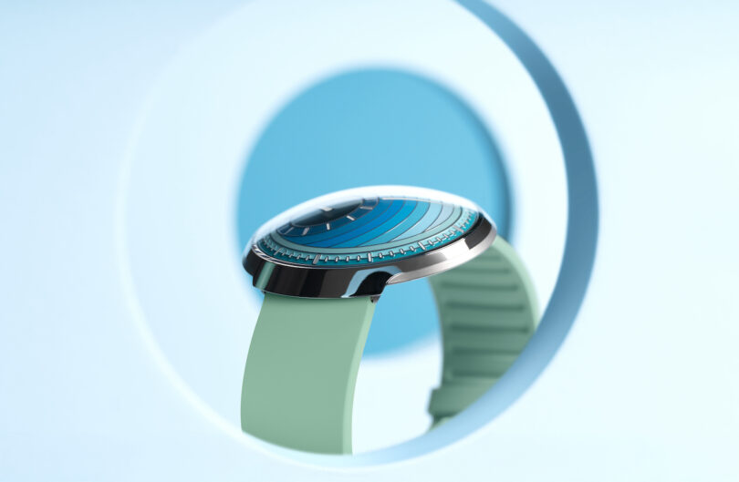 A modern wristwatch with a turquoise band and a circular, futuristic face is displayed against a light blue background with geometric shapeS