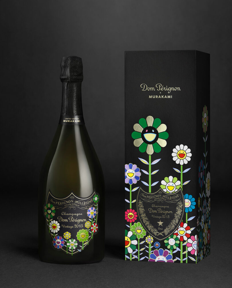 A Takashi Murakami Dom Perignon Vintage 2015 champagne bottle stands beside its box, both adorned with vibrant Murakami flower artwork on a sleek black background.