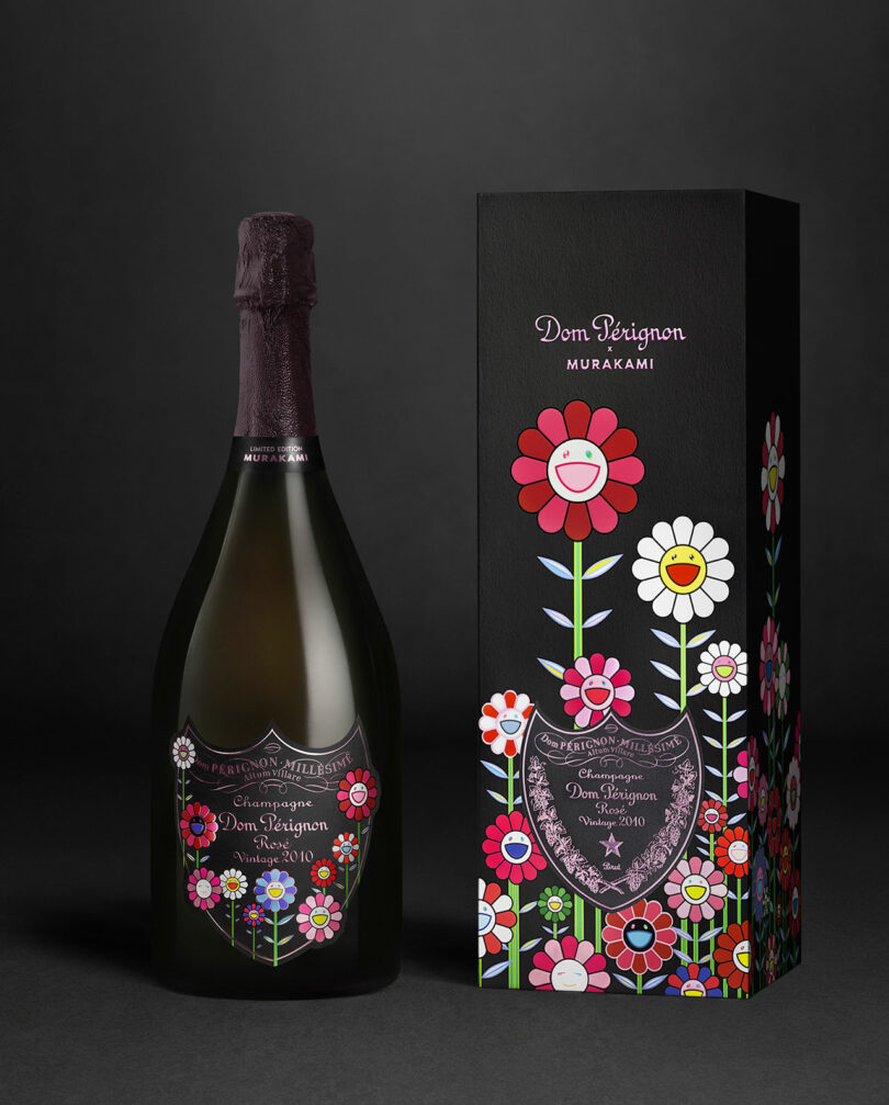 A bottle of Takashi Murakami Dom Perignon Vintage 2010 Champagne stands next to a gift box adorned with colorful, smiling flowers by the renowned artist Murakami.