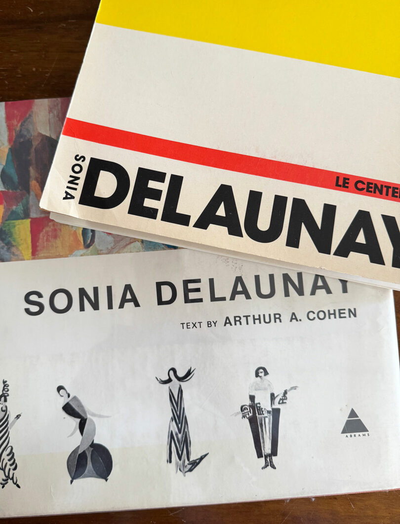 Close-up of two books about Sonia Delaunay, one featuring bold text and the other with stylized illustrations of women on the cover.