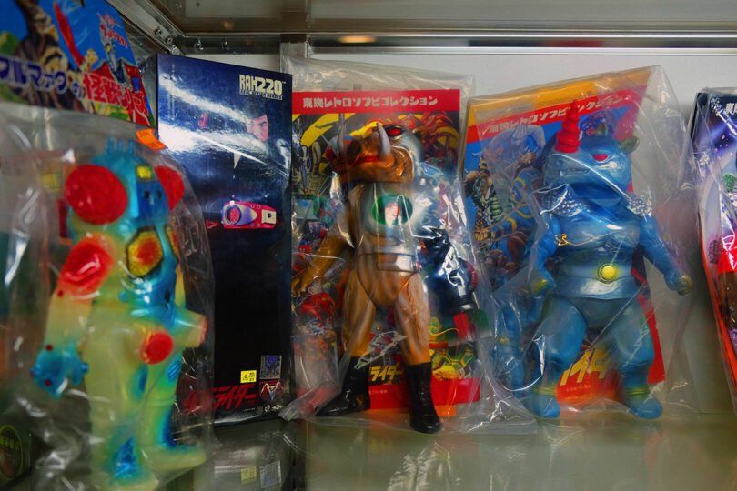 Three colorful vintage Japanese action figures in clear plastic bags are displayed upright on a shelf with illustrated backing cards behind them.