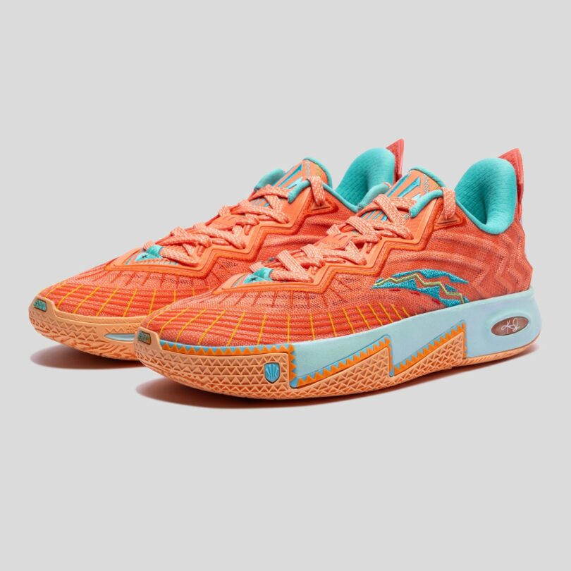 A pair of orange athletic sneakers with blue accents and zigzag patterns, set against a plain gray background