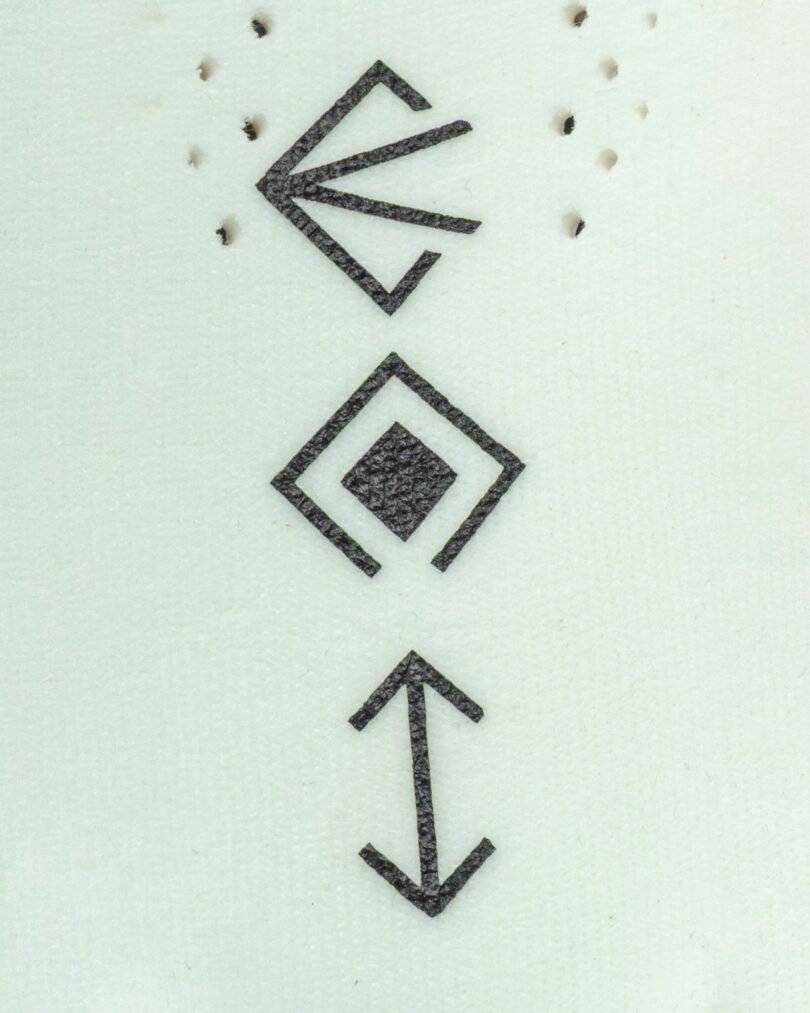 Three black geometric symbols arranged vertically on a white textured background: a fan shape, a diamond with a square inside, and two arrows pointing in opposite directions