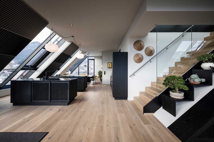 modern apartment interior with slanted glass walls and black kitchen