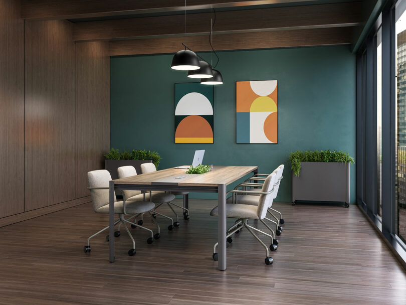 Modern conference room with a wooden table, six chairs, abstract artwork on the wall, two planters, and large windows letting in natural light.