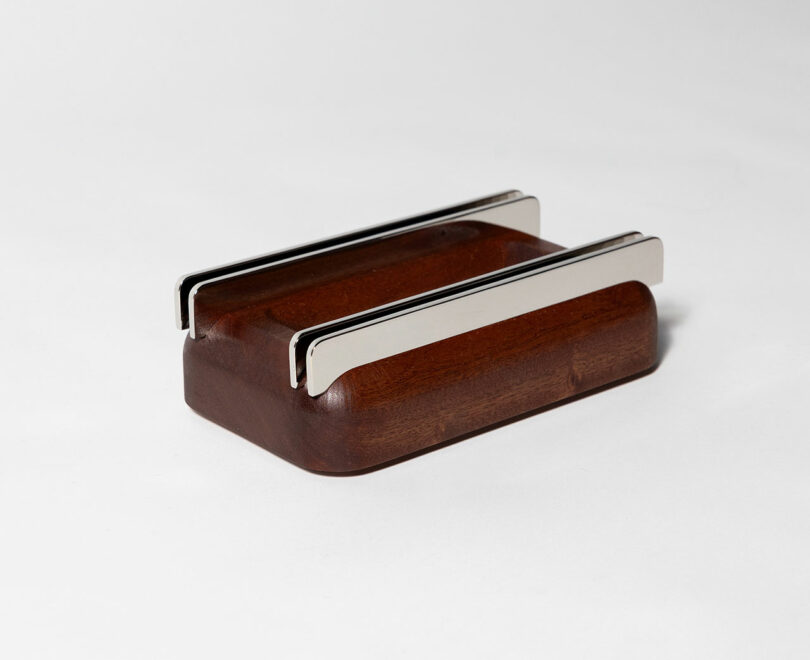 A wooden rectangular base with two parallel metal bars attached on top, placed on a plain white background.